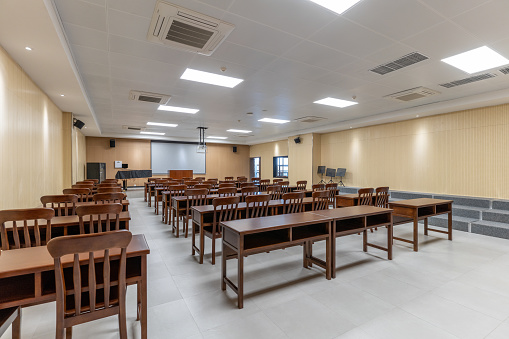3d rendering of new normal classroom interior and spacing tables and chairs to prevent the spread of the covid-19 virus on wood floor and empty green board background.