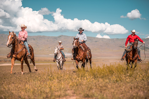 Cowboys and cow girls are riding horses. Beautiful nature in the back in Utah, USA.