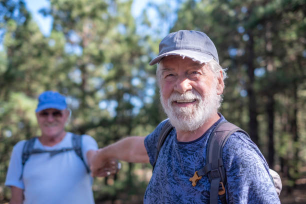 istock Happy smiling couple of elderly men with hat and backpack look in camera while enjoying mountain hike in the woods appreciating adventure and freedom, retired seniors and healthy lifestyle concept 1445765854