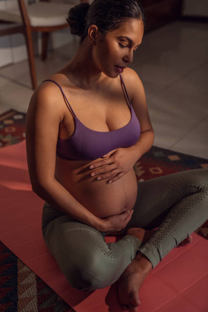 Beautiful pregnant woman doing breathing exercises at home. stock photo