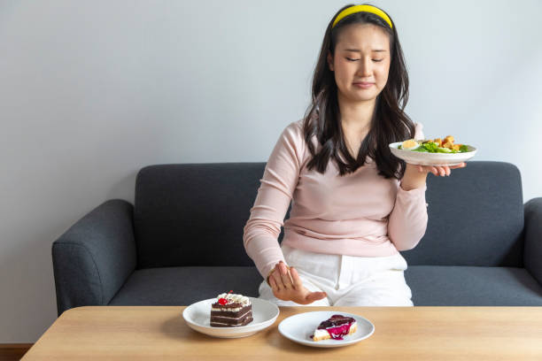 istock Diet concept. Women refuse cake and eat salad for good health. 1445766310