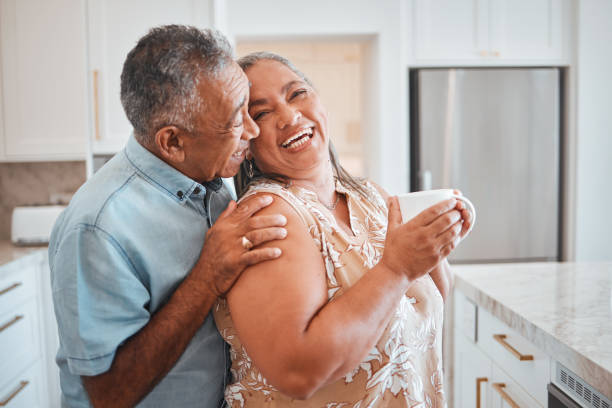 Love, laughing and elderly couple embrace in kitchen, having fun, talking and being silly together. Happy family, relax and retirement by senior man and woman enjoy conversation and relaxed lifestyle