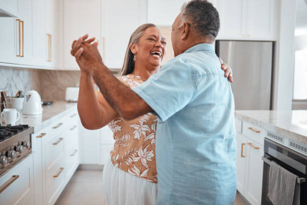 glückliches älteres paar, tanz und lachen in freudigem glück für beziehungsbindung in der küche zu hause. älterer mann und frau mit lächeln tanzen zusammen für romantische momente in liebe und fürsorge - dancing couple happiness heterosexual couple stock-fotos und bilder