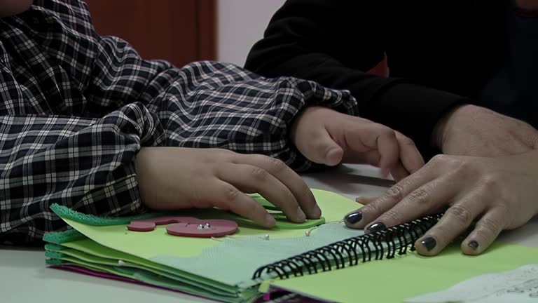 Teacher Assisting Kindergarten Kid Reading Braille Alphabet at a Public School for the Blind and Visually Impaired Children in Argentina. Close Up.