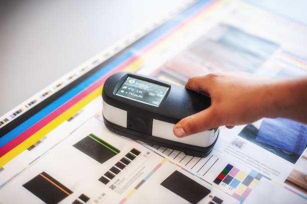 Color management. X-Rite handheld Spectrophotometer verify color, Print Measuring Tool X-Rite handheld spectrophotometer verify color patches, modern press shop prepress department. proof reading documents stock pictures, royalty-free photos & images