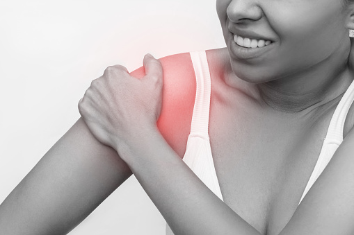 Shoulder injuries. Cropped shot of a young caucasian woman holding a shoulder in her hand isolated on a white background. Arm pain, neuralgia, sports trauma, joint disease. Black and white shot
