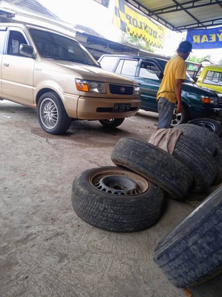 Toyota Kijang LGX  replaced with wheels March 16, 2021-Magelang, Central Java, Indonesia - The cream-colored Toyota Kijang LGX is being replaced with wheels and tires at the tire repair shop kijang stock pictures, royalty-free photos & images