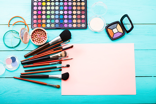 Makeup tools on blue wooden background. Top view, copy space and mockup. Woman beauty accessories. Eye shadows.