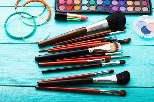 Make-up tools. Make up products. Lipstick, eye shadow, brushes.Cosmetics on blue wooden background.Selective focus