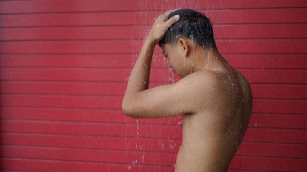 Sport man take a rain shower for cleaning at the swimming pool in hotel. stock photo