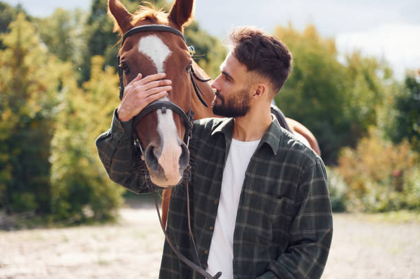 istock Front view. Young man with a horse is outdoors 1445776181