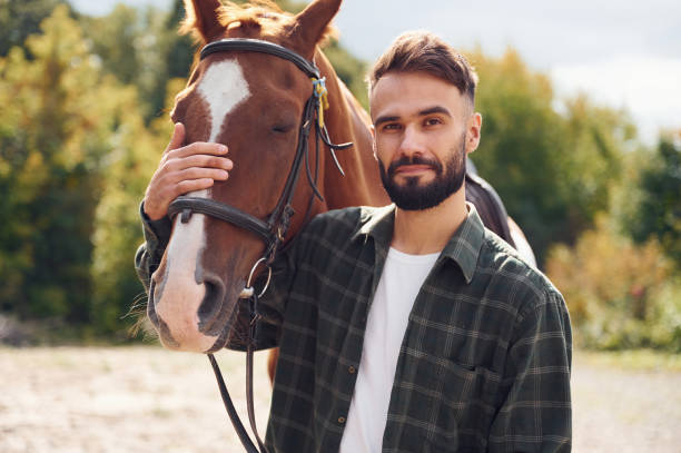 istock Front view. Young man with a horse is outdoors 1445776183