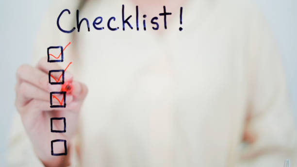 Business woman writing plan checklist on glass board in office