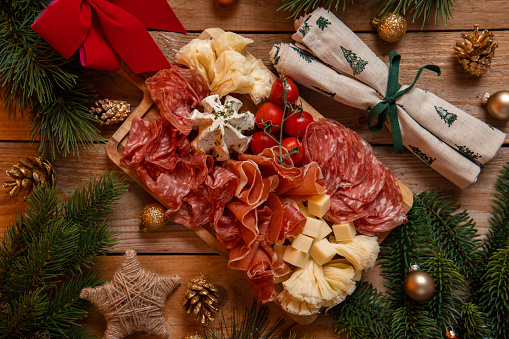 Appetizer Charcuterie Board with ham, salami and cheese for festive Christmas celebration in rustic kitchen