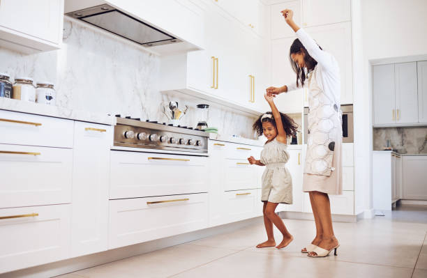 dance, playful child and mother being comic, crazy and free with a girl in the kitchen together at home. care, love and happy kid dancing with her mom in freedom while listening to music in house - parent mother music listening imagens e fotografias de stock