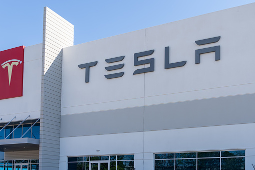 Houston, Texas, USA - March 2, 2022: Closeup of Tesla sign on the building with blue sky in background. Tesla, Inc. is an American electric vehicle and clean energy company. Editorial use only.