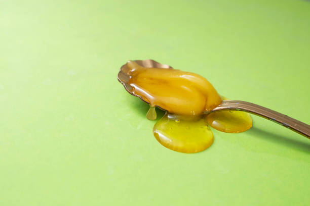istock Honey on a golden spoon, on light green background, 1445782154