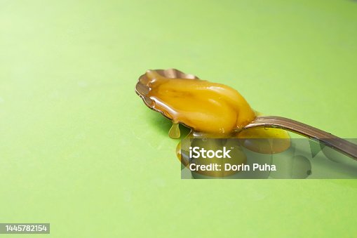 istock Honey on a golden spoon, on light green background, 1445782154
