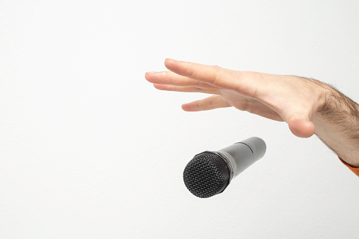 La mano del hombre caucásico dejando caer el micrófono, la mano estirada y un micrófono photo