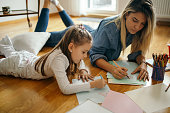 Woman spending some great time with little girl at home and they are drawing together