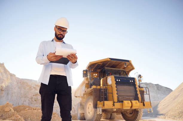 Smart person is with documents in hands. Man in uniform is working in the quarry at daytime stock photo
