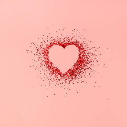 The heart-shaped in red shiny glitter on a pastel pink background. \nMinimal Valentine's day, mother's day, or birthday concept. Pink aesthetic.