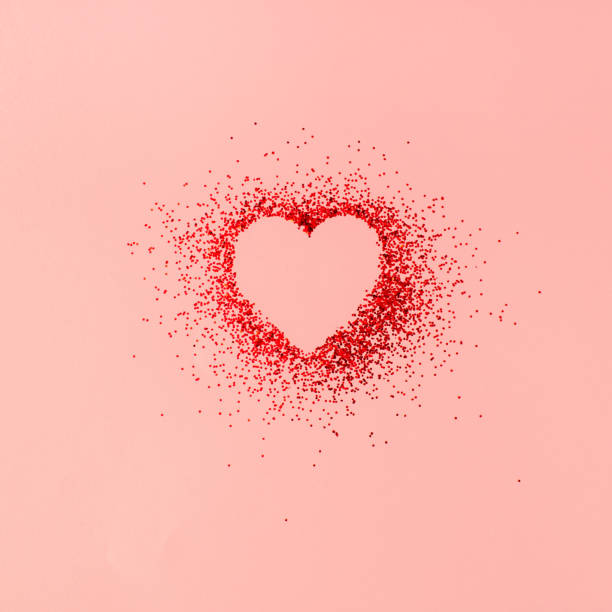 The heart shaped in red shiny glitter on pastel pink background The heart-shaped in red shiny glitter on a pastel pink background. 
Minimal Valentine's day, mother's day, or birthday concept. Pink aesthetic. gift vibrant color red pink stock pictures, royalty-free photos & images