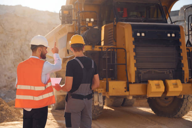 istock Standing near haul truck and talking about document. Two men in uniform are working together in the quarry 1445793201