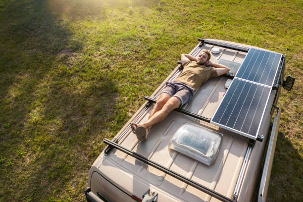 Man relaxing on the roof of a camper van stock photo