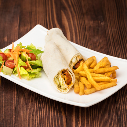 Shish tawook shawarma sandwich roll wrap with salad and fries served in dish isolated on table top view of fastfood