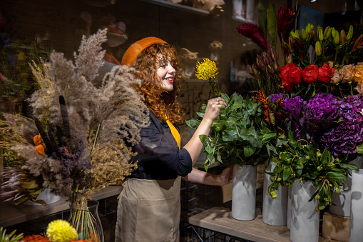 Flower shop. Pretty girl in an orange beret in a flower shop