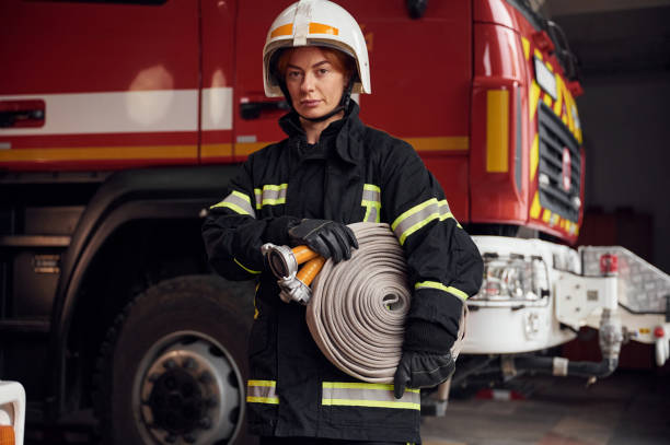 灰色の消防ホースが手にあります。制服を着た女性が部門で働いている - fire hose fire fire department fire station ストックフォトと画像