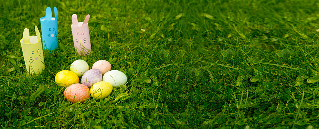 DAY paper rabbits on the grass with colorful eggs. Festive Easter concept.