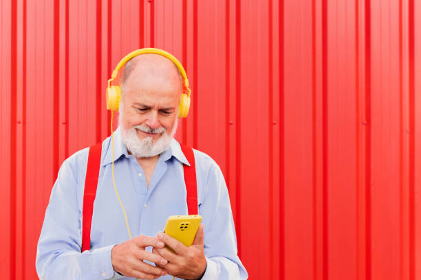 istock Senior man using mobile smartphone while listening music playlist with headphones- Elderly people lifestyle and tech concept 1445797128
