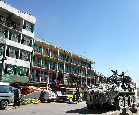 Kabul / Afghanistan: An armored vehicle drives along a street in Kabul, Afghanistan. Civilians carry on with everyday life. Armoured vehicle, tank, war, street, people, Kabul Afghanistan