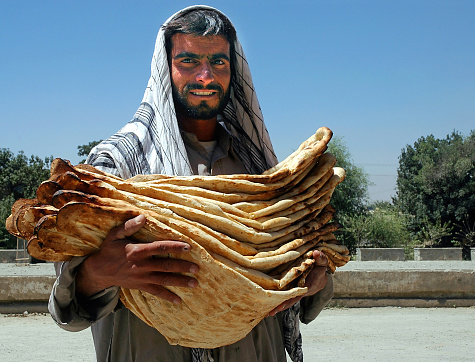 Kabul / Afghanistan: Man selling bread in Kabul, Afghanistan. The bread seller is carrying many very large flat pieces of bread. Bread seller, afghan naan, flatbread, Kabul, Afghanistan.