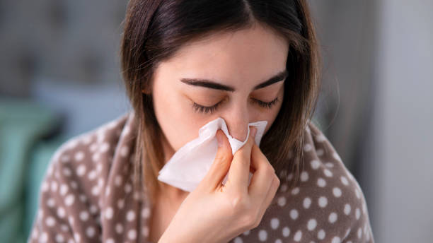 istock Young sick woman blowing her nose while in bed 1445802320