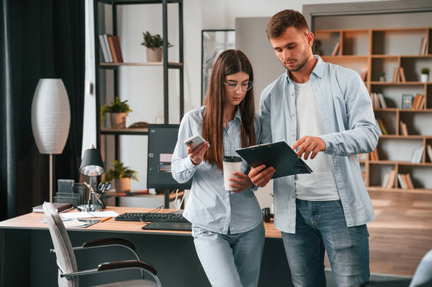 istock Standing and holding notepad. Two young designers is working together in the office 1445802511