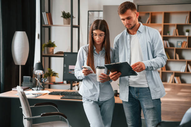 istock Standing and holding notepad. Two young designers is working together in the office 1445802516