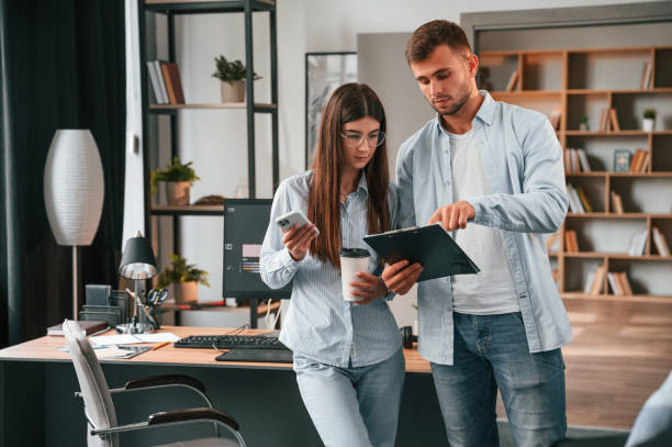 istock Standing and holding notepad. Two young designers is working together in the office 1445802539