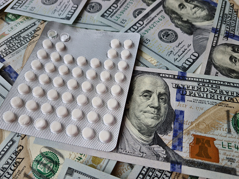 Dollar bills among blisters with white pills world conspiracy. Power of money in medicine secret government