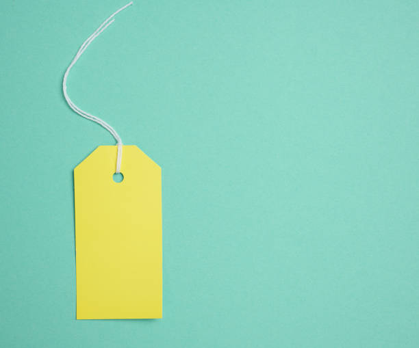 istock Empty yellow cardboard tag on a white rope, green background. Price tag template 1445805756
