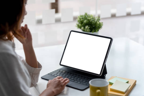istock Businesswoman sitting at work using a tablet in front of a white screen. 1445806262