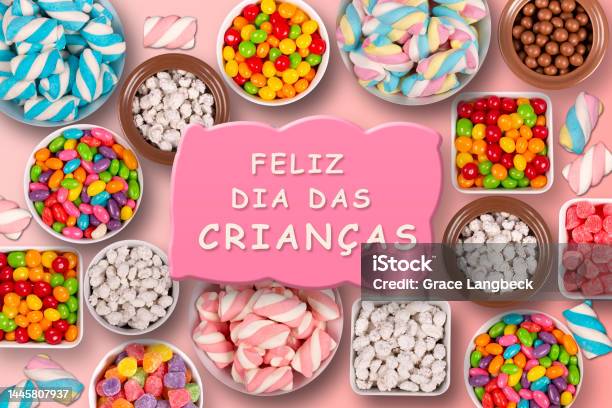 Colorful Candies Marshmellows Chocolate Balls In Jars Lollipops And Sweet Peanuts Written Happy Childrens Day In Portuguese Stock Photo - Download Image Now