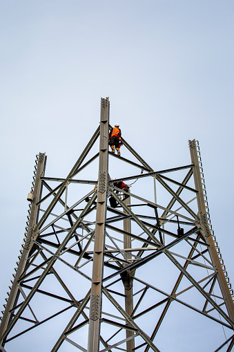 Sindlingen, Germany - November 08, 2022: Workers assemble a pylon for electricity transmission near Sindlingen in Germany. Proportion of renewable energy sources used in electricity generation in Germany is currently increasing much faster than the necessary grid expansion to transport it, therefore Germany is expanding its national power grid as a necessary infrastructure measure.