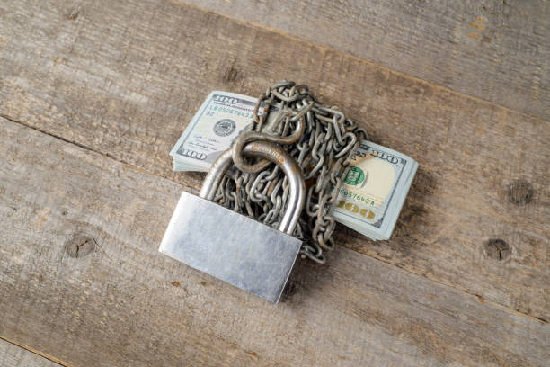 istock Dollars and a big silver lock on wooden table. copy space. 1445811648