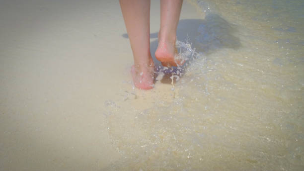 Close up of a woman walking on exotic white sandy beach in Maldives. Close up of a woman walking on exotic white sandy beach in Maldives. Splashes and waves of clear water. Summer travel vacation concept. slow walk stock pictures, royalty-free photos & images