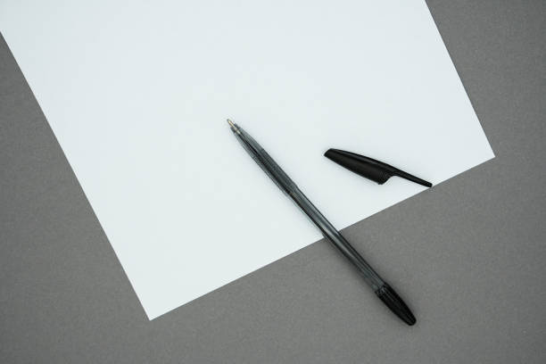 istock Blank white paper and pen on gray background. Copy space for text, top view of workspace 1445815390