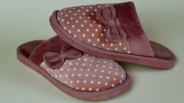 Women's house slippers with a beautiful pink pattern with white polka dots and a bow. Pair of female slippers for house. Modern indoor shoes for walking around the house, soft, warm and comfortable