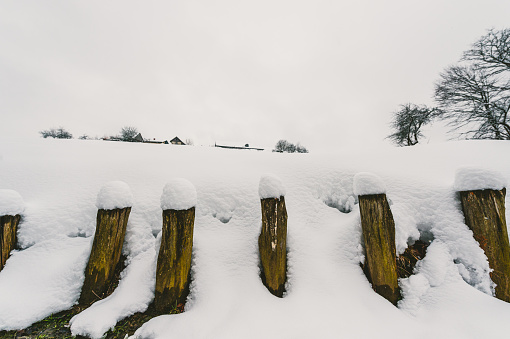Tree trunk fence covered in snow